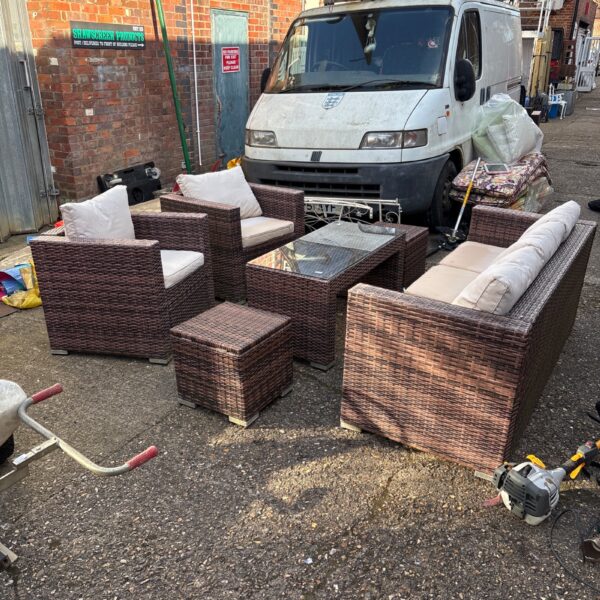Full view of a brown rattan garden furniture set on a patio.