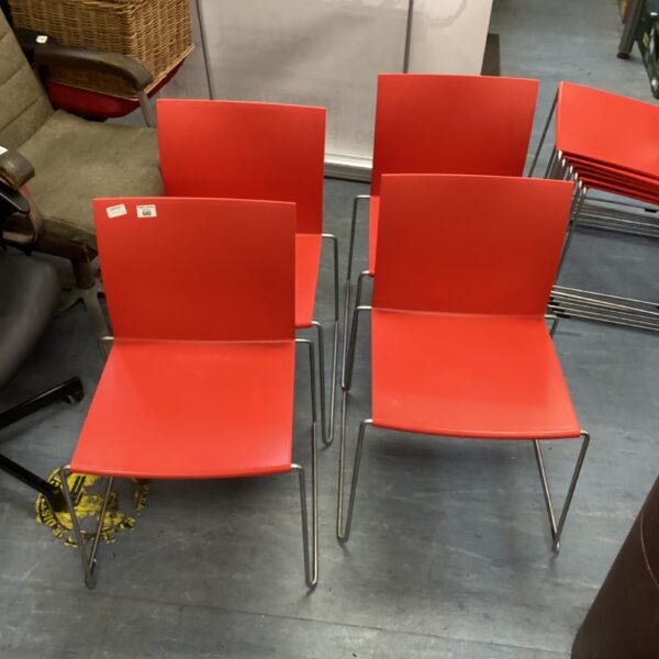 Set of four red chrome chairs with plastic seats.