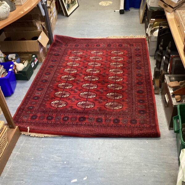 Red geometric rug with repeating pattern, vintage floor covering.