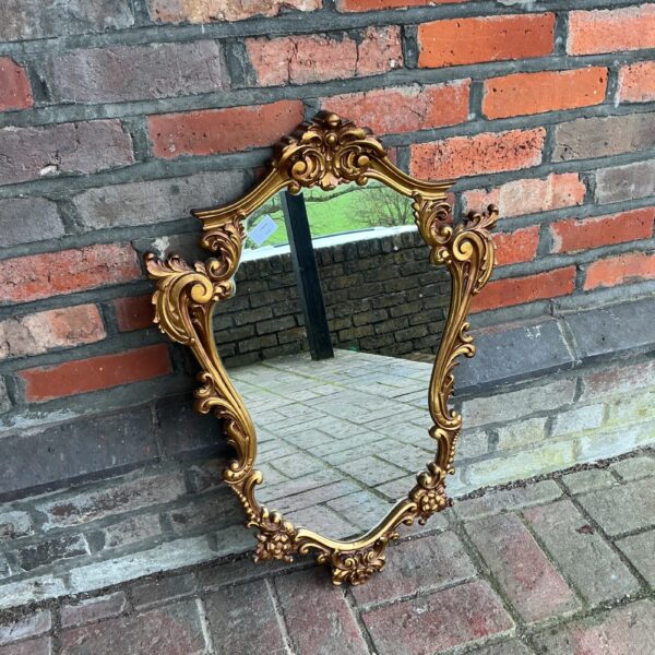 Ornate Rococo style mirror with gilded frame and floral details.