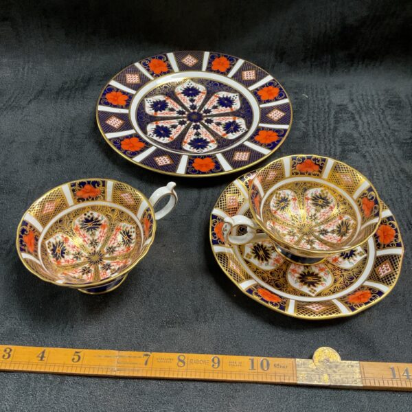 Royal Crown Derby Old Imari plate, saucer, and cups on a vintage background.