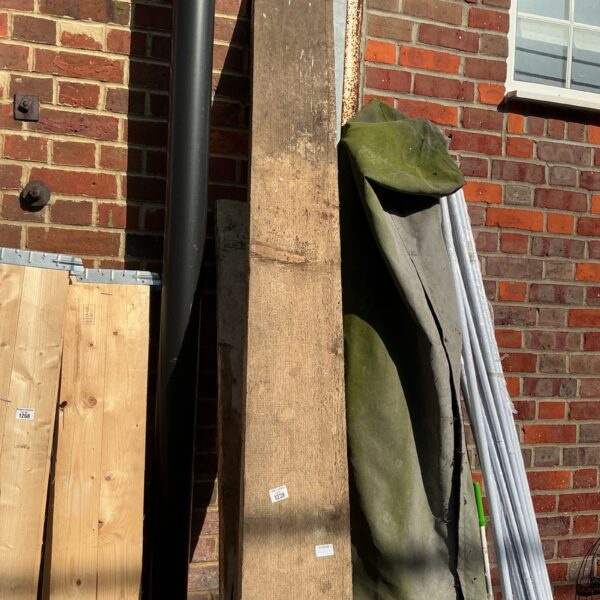 Two used scaffolding planks leaning against a brick wall.