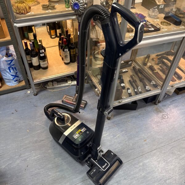 Shark upright hoover in a cluttered auction setting.