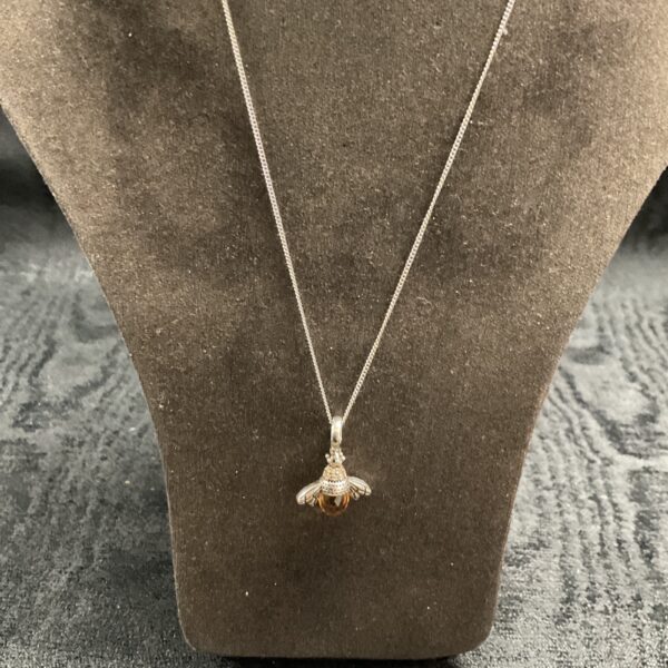 Close-up of silver amber moth pendant on a necklace.