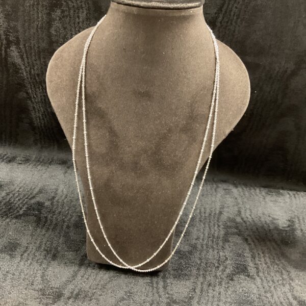 Pair of delicate silver ball link necklaces on a display bust.
