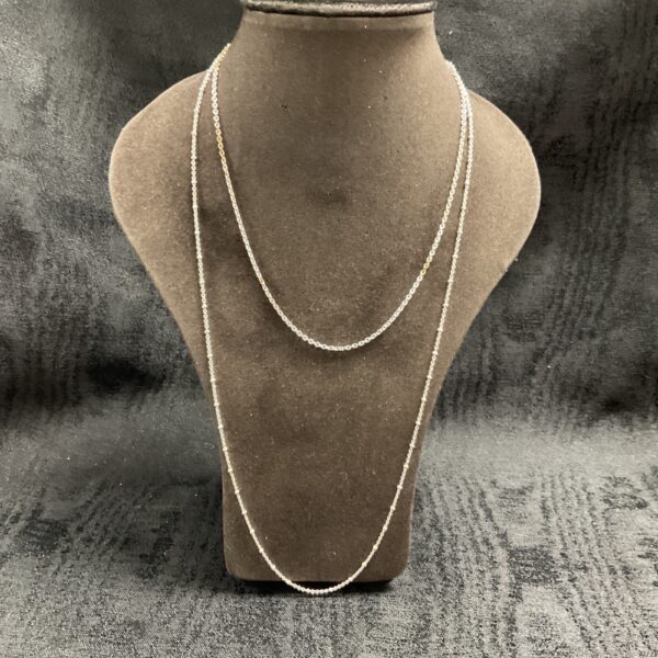 Two delicate silver ball link necklaces displayed on a mannequin.
