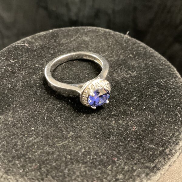 Silver ring with a vibrant blue stone and white halo.