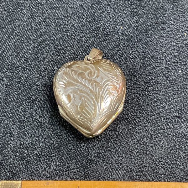 Vintage silver clover locket with floral engraving.