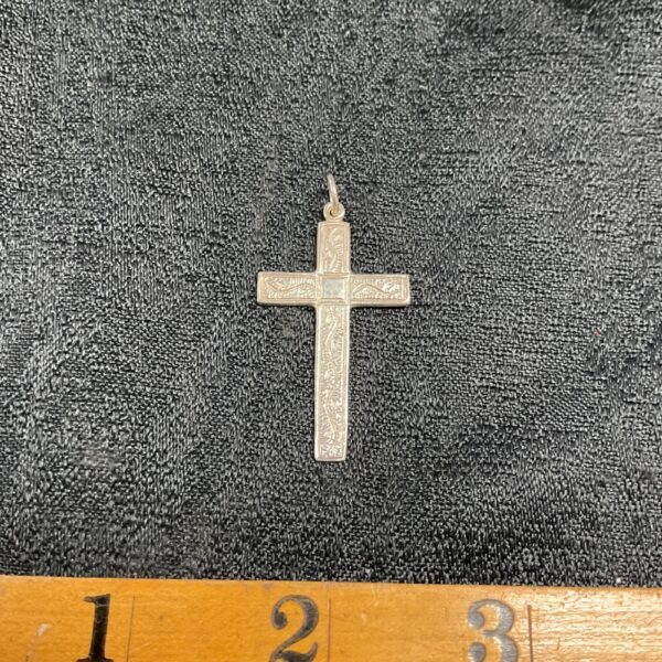 Detailed silver cross pendant with intricate relief work.