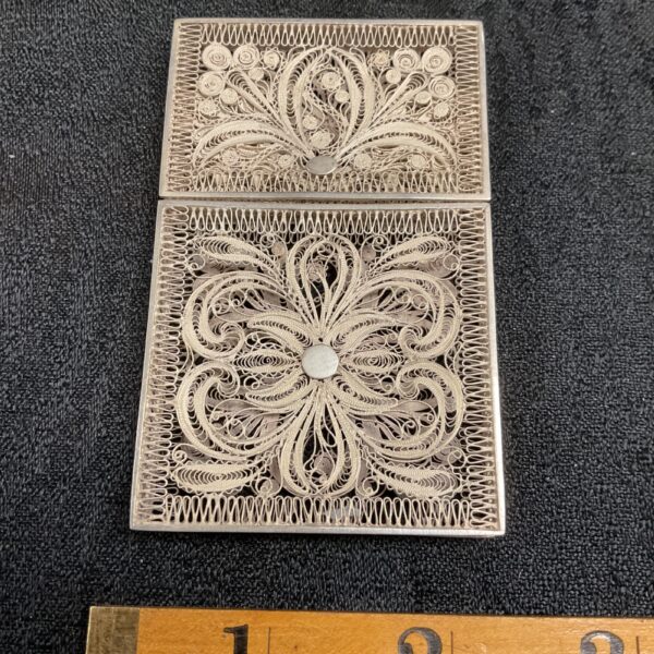 Intricate silver filigree card case with detailed openwork design.
