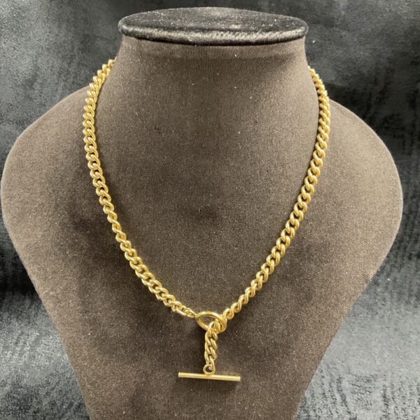 Elegant silver gilt T bar necklace on a neutral background.