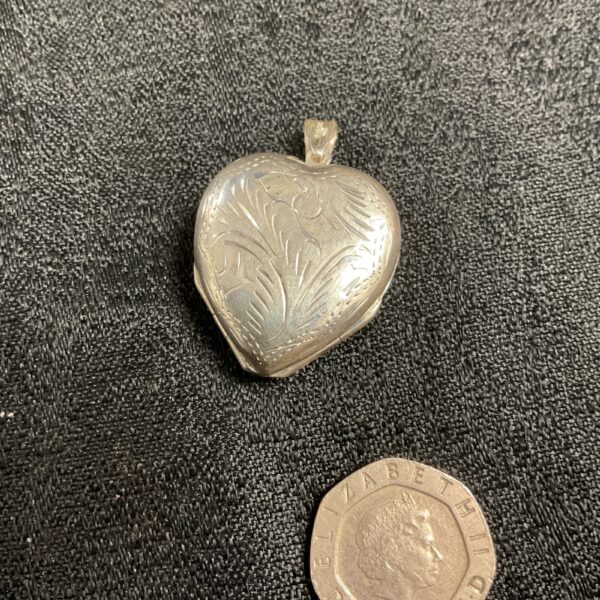 Silver heart locket with embossed cloverleaf design.