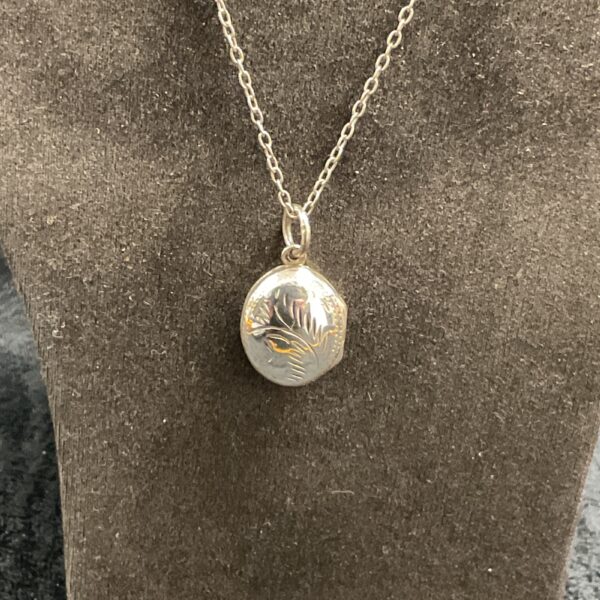 Vintage silver locket necklace with heart pendant on chain.