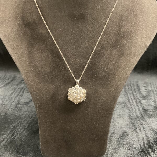 Delicate silver pendant necklace with white stones and floral design.