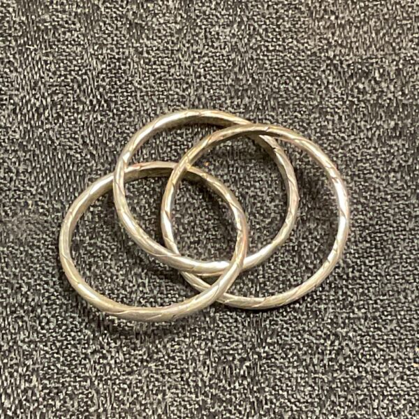 Close-up of antique silver puzzle ring with interlocking bands.