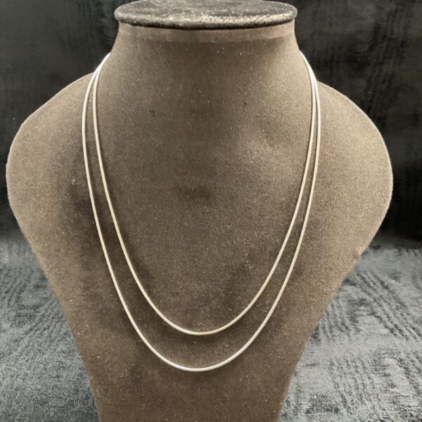 Pair of delicate silver snake chain necklaces on display.