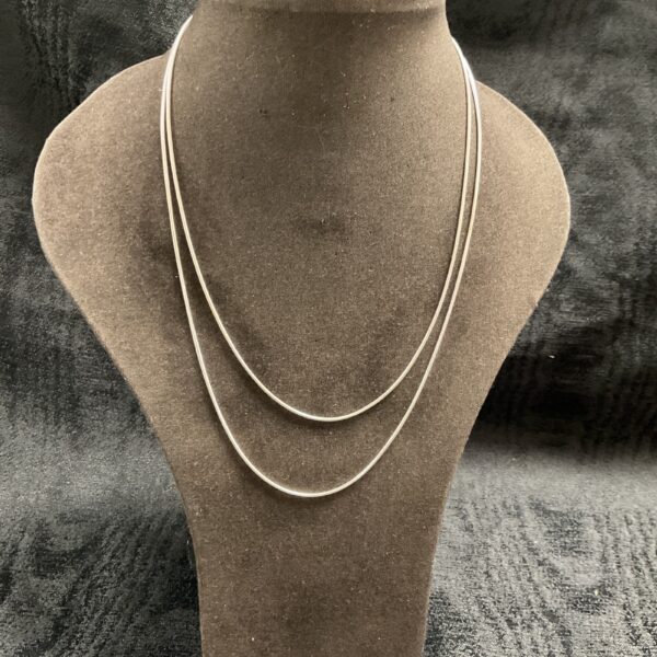 Pair of delicate silver snake chain necklaces on display.
