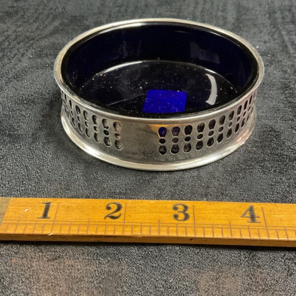 Antique silver wine bottle coaster with pierced detail and blue glass.
