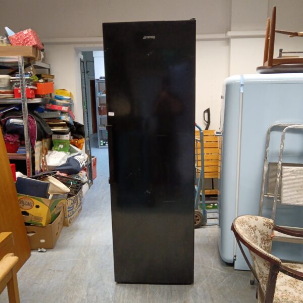 Large black Smeg fridge in a cluttered kitchen setting.