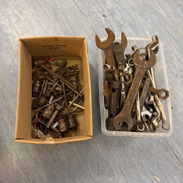 Assorted spanners and drill bits in a tool lot.