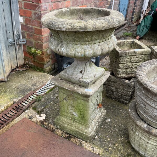 Tall stone garden planter with plinth, weathered outdoor decor.