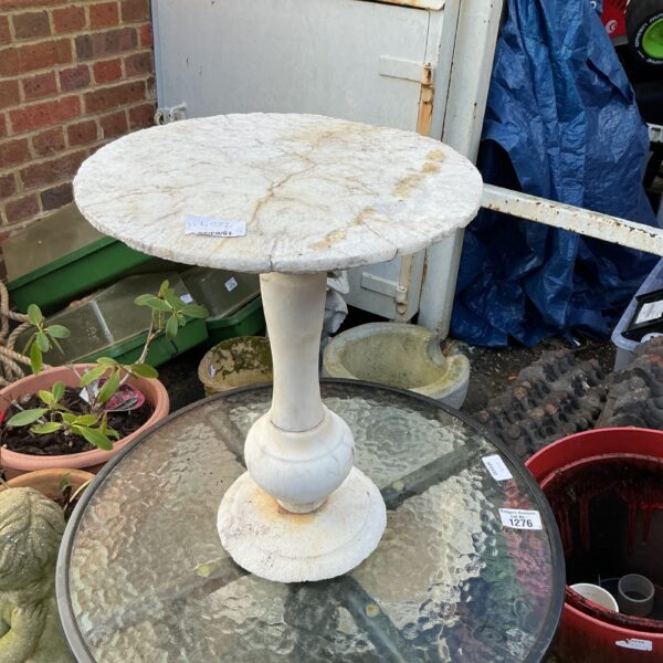 Small stone plant stand in a garden setting.