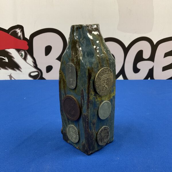 Front view of a green studio pottery vase with embedded coins.