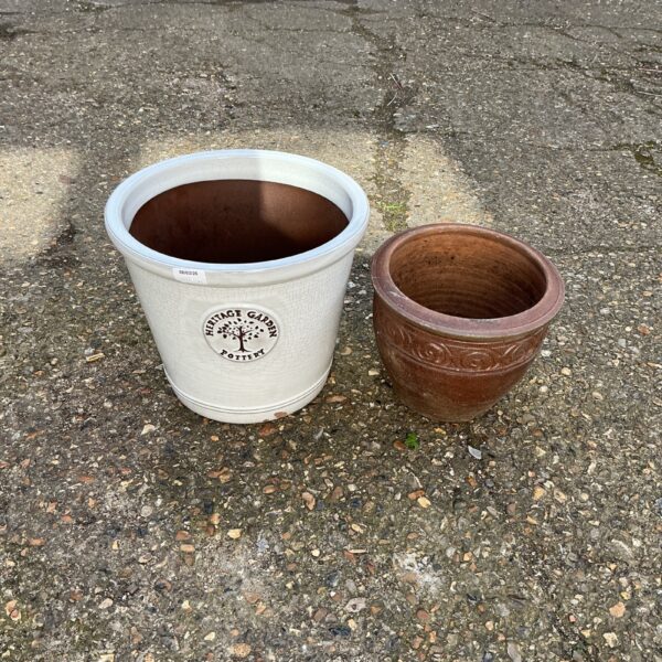 Two weathered terracotta garden pots in an outdoor setting.
