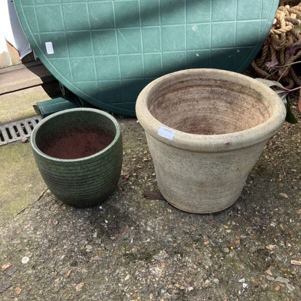 Two weathered terracotta garden pots in a garden setting.