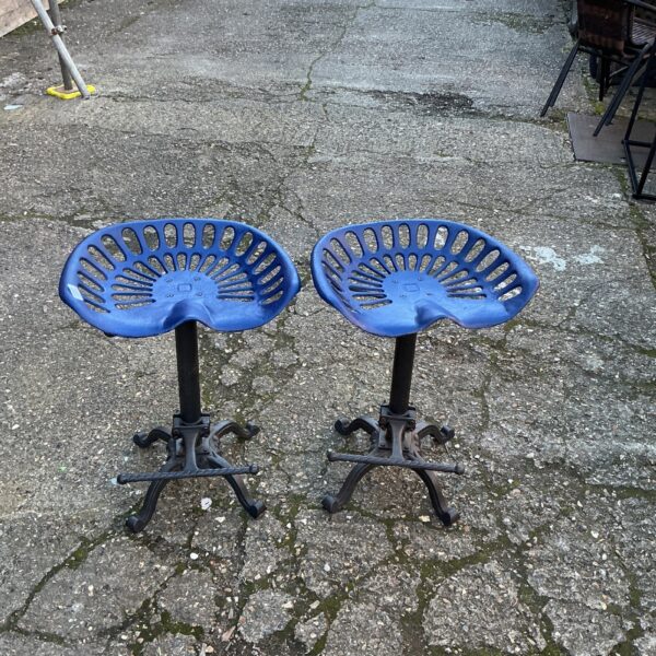 Pair of vintage tractor seat bar stools with metal bases.