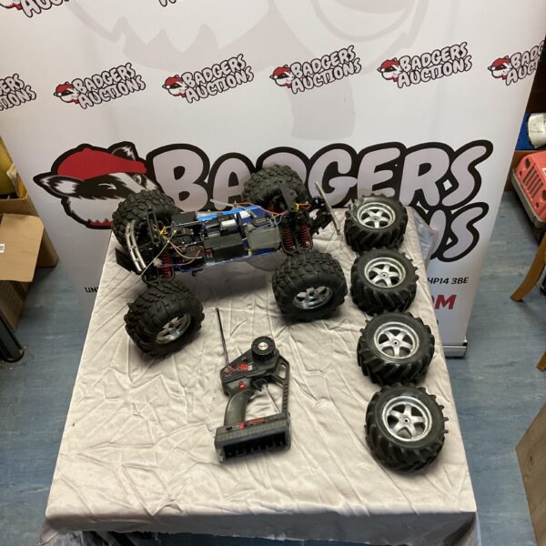 Traxxas RC truck base with remote control and spare wheels.