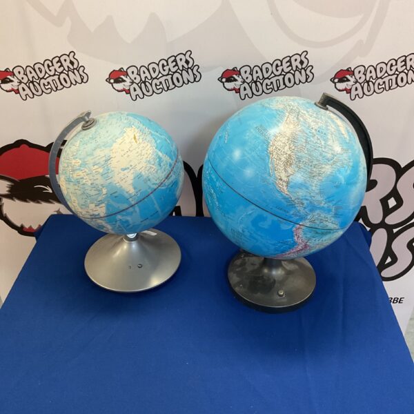 Two illuminated light up globes on a display surface.