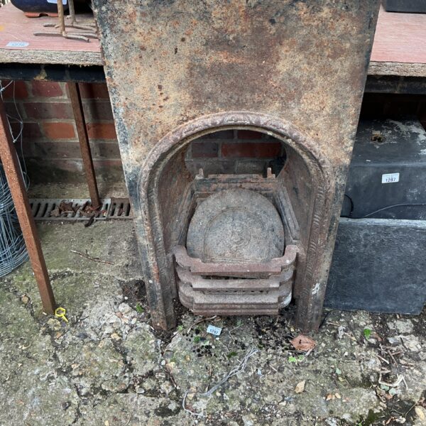 Front view of a Victorian metal fireplace insert with decorative grate.