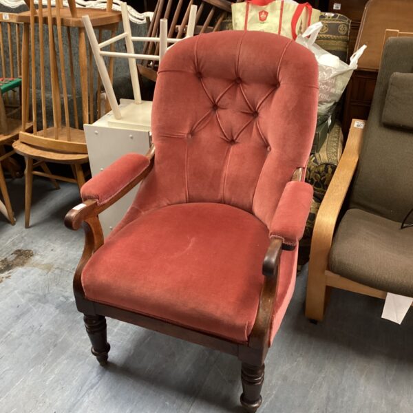Pink Victorian upholstered armchair with rolled arms.