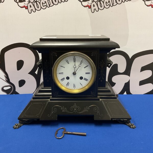 Victorian slate mantle clock with lion head carvings and claw feet.