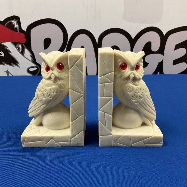 Vintage alabaster owl bookends on a patterned surface.