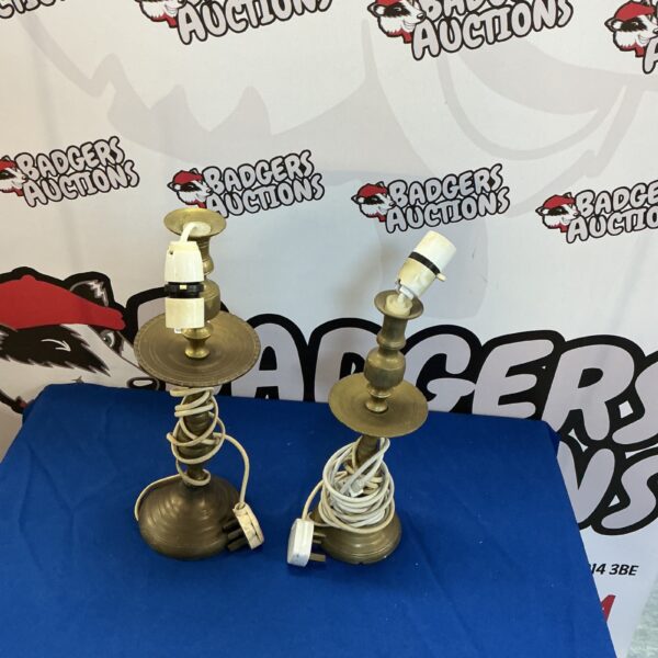 Pair of vintage brass candlestick lamps on a dark surface.