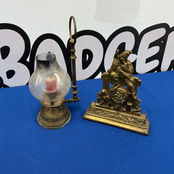 Vintage brass oil lamp and doorstop with ornate detailing.