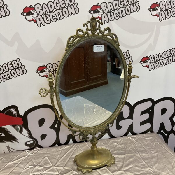 Vintage brass pedestal mirror with ornate detailing.