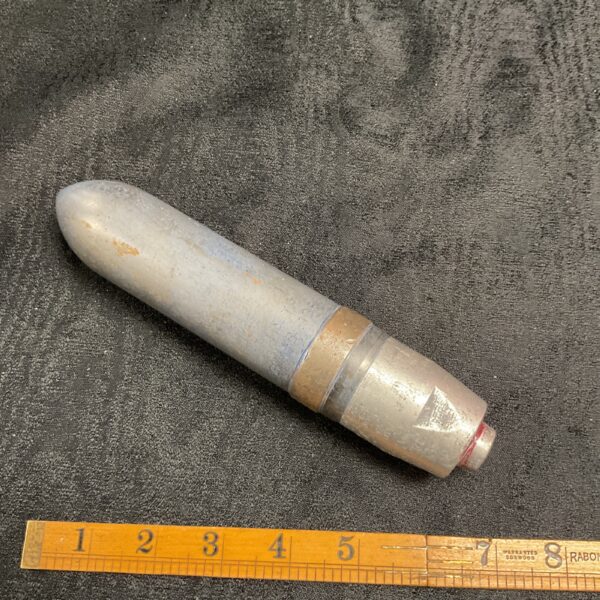 Vintage cannon shell tip with ruler for scale.