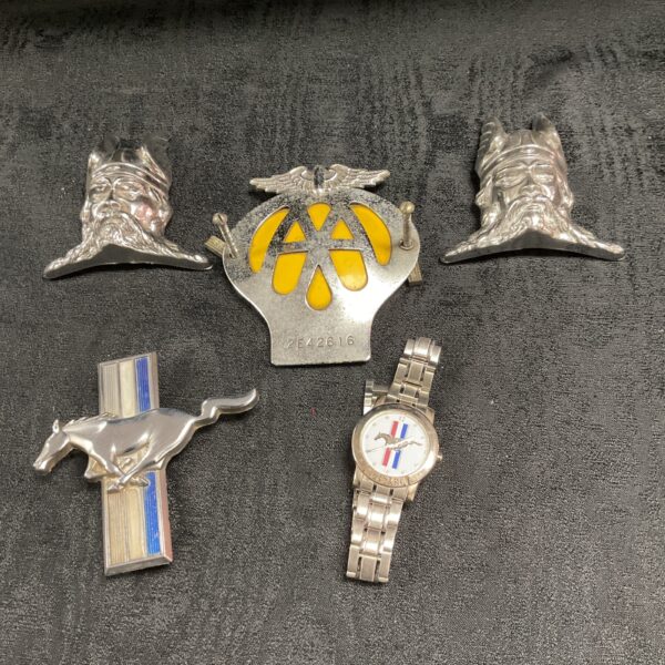Vintage car badges and wristwatch collection for automotive enthusiasts.