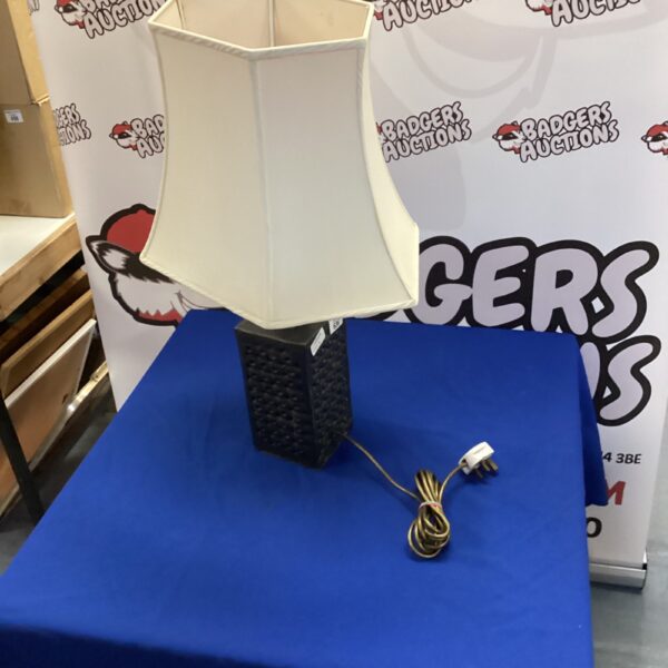 Vintage ceramic table lamp with off-white shade on blue background.