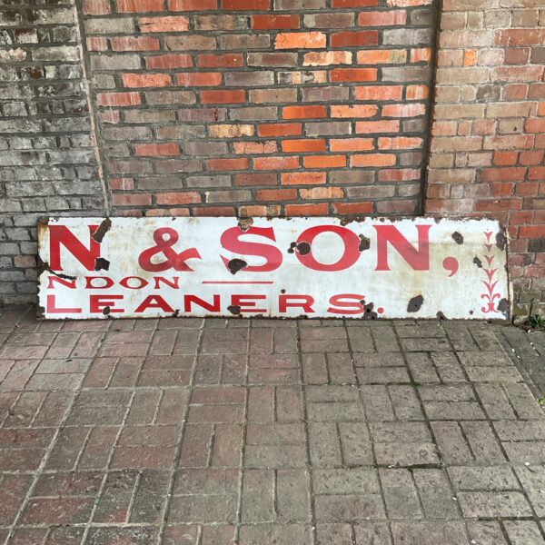 Large vintage enamel shop sign with red and white lettering.