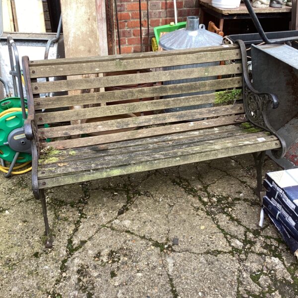 Vintage garden bench with decorative wrought iron ends in a garden setting.