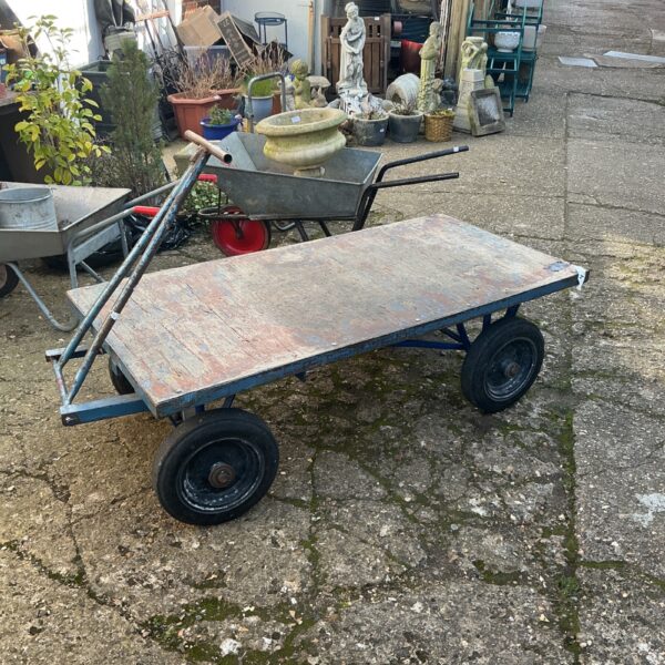 Vintage garden trolley cart with wooden platform and wheels.