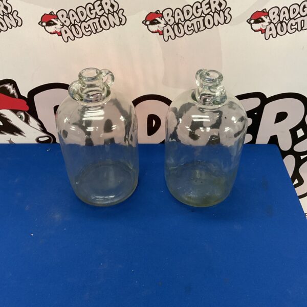 Two clear glass vintage demijohns for wine or cider.