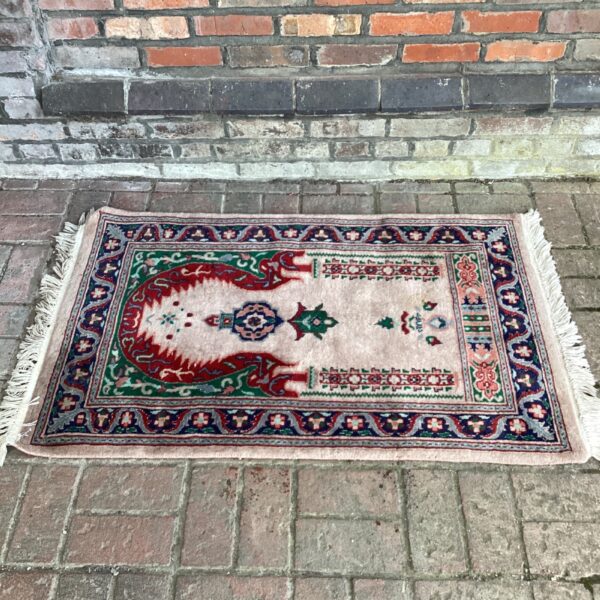 Vintage Islamic rug with tassels, detailed floral design.