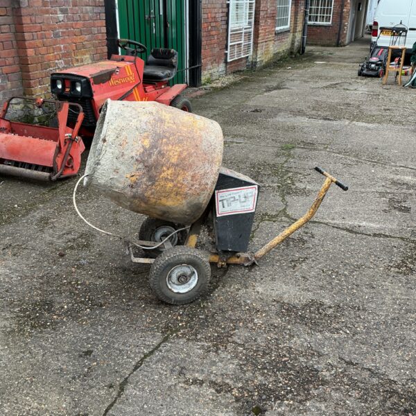 Vintage Little Bedford cement mixer in a garden setting.