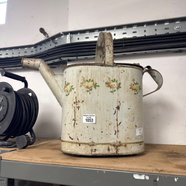 Vintage metal watering can with floral design for garden use.