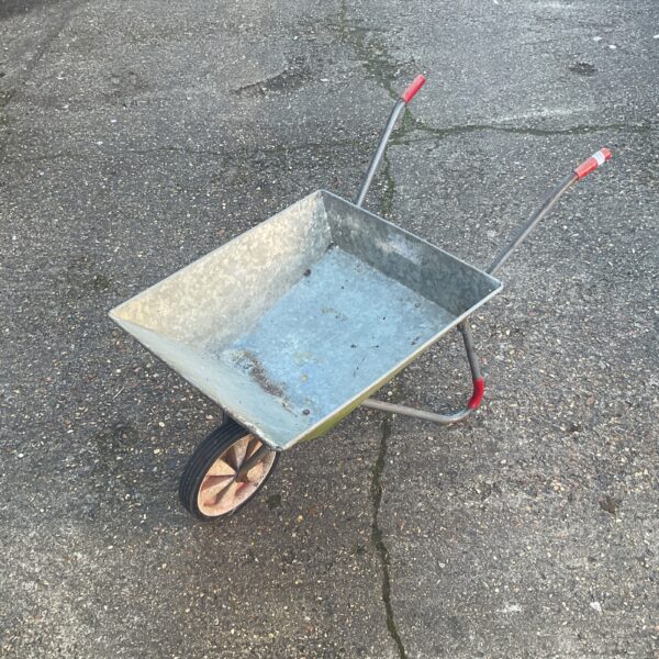 Vintage metal wheelbarrow with a single wheel, rustic garden tool.